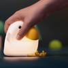 Twinkle Glory Cuckoo silicone night light being squeezed by a hand, showing soft material and warm yellow glow.
