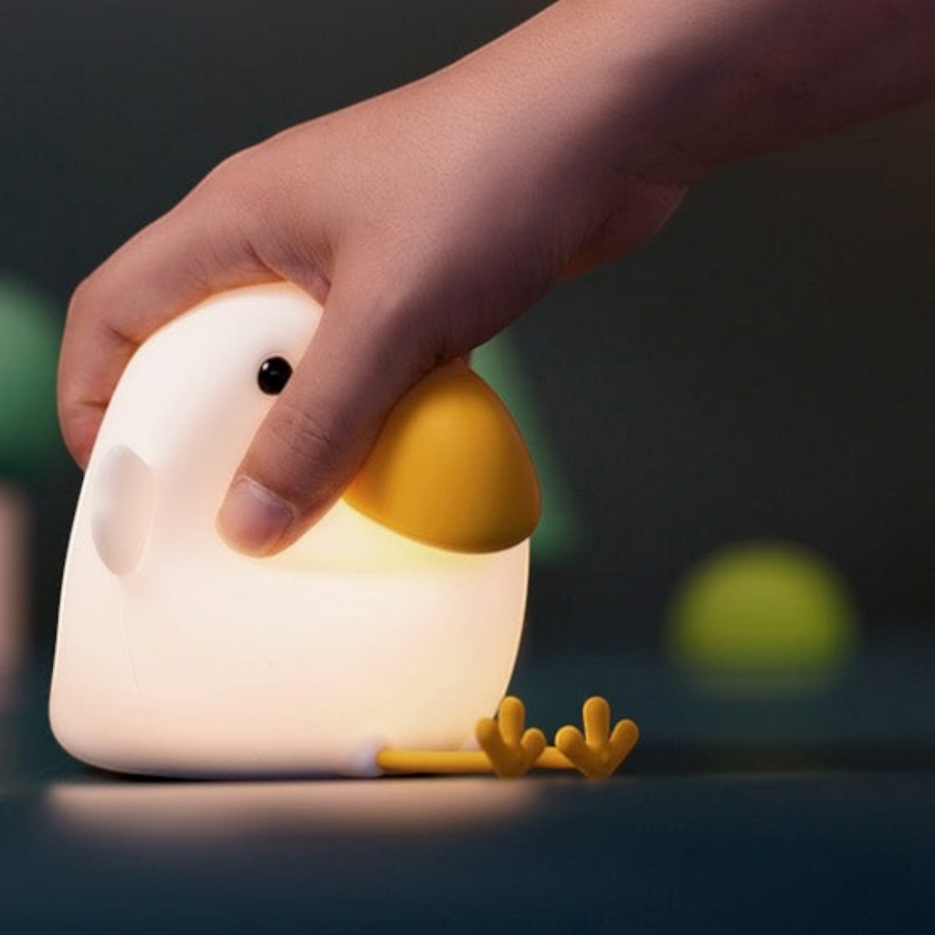Twinkle Glory Cuckoo silicone night light being squeezed by a hand, showing soft material and warm yellow glow.