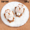 Two plush toys resembling cartoon characters on a white fluffy surface with 'Top Toy' and 'Disney' branding.