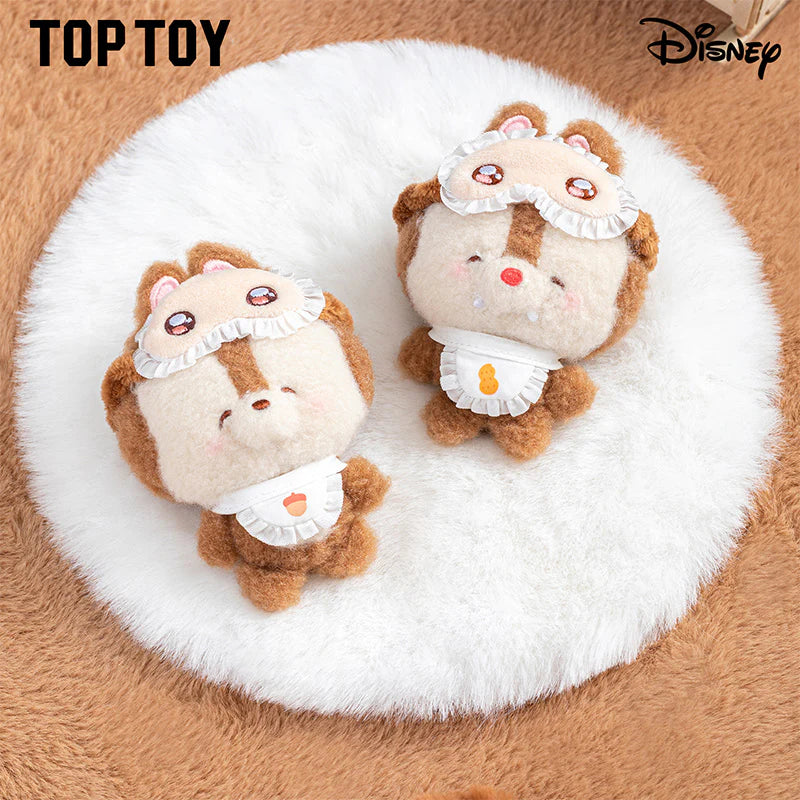 Two plush toys resembling cartoon characters on a white fluffy surface with 'Top Toy' and 'Disney' branding.