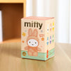 Box of a plush toy with 'miffy' branding on a wooden surface.
