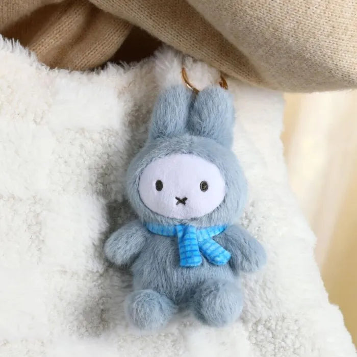 Plush toy rabbit with a blue scarf on a soft surface