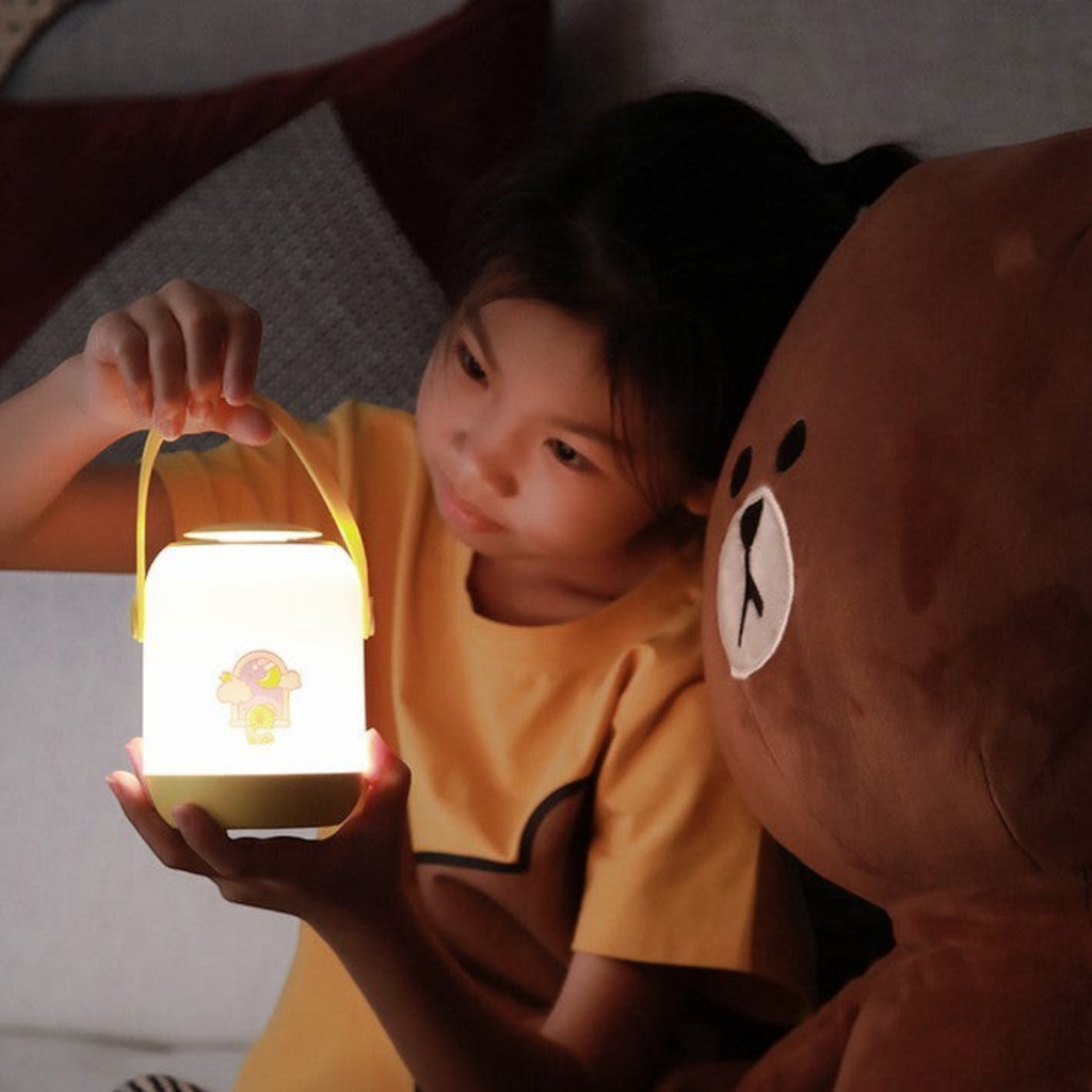 Twinkle Glory Line Friends round handle soft LED night light held by a child next to a Brown bear plush toy