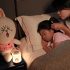 Twinkle Glory Line Friends soft LED night light with round handle glowing on a bedside table next to a sleeping child