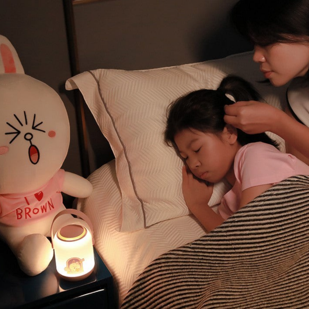 Twinkle Glory Line Friends soft LED night light with round handle glowing on a bedside table next to a sleeping child