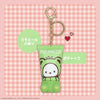 Pochacco keychain with green pouch on a pink checkered background