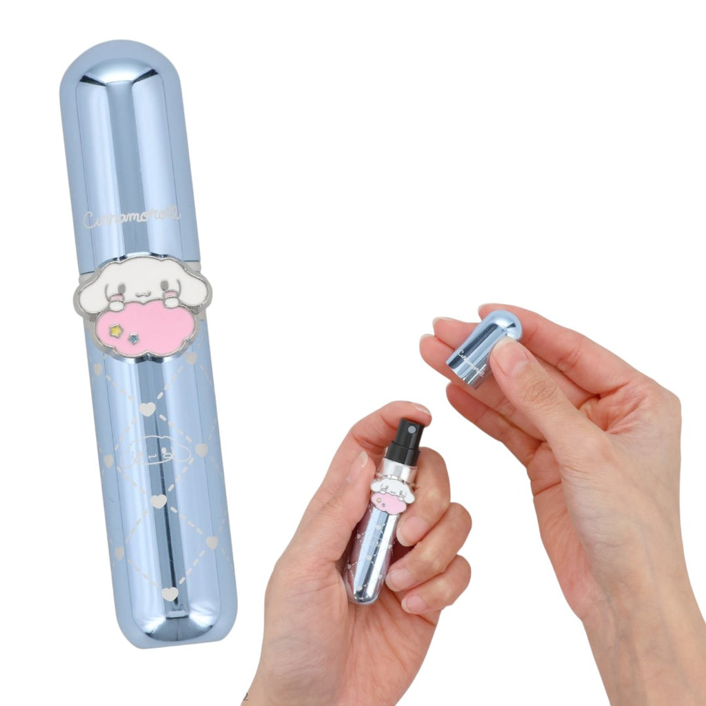 A small cylindrical perfume or fragrance bottle with a metallic silver cap and a black spray nozzle, shown with a matching decorative cloud-shaped cap being held by two hands. The bottle has a pale blue reflective finish with a heart and cloud design and the text 'Cotton Candy' visible on the side.