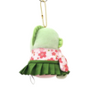 A small plush character keychain or bag charm shown against a plain white background. The plush has a light green top, a dark green pleated skirt, and a pink fabric band with red floral print.