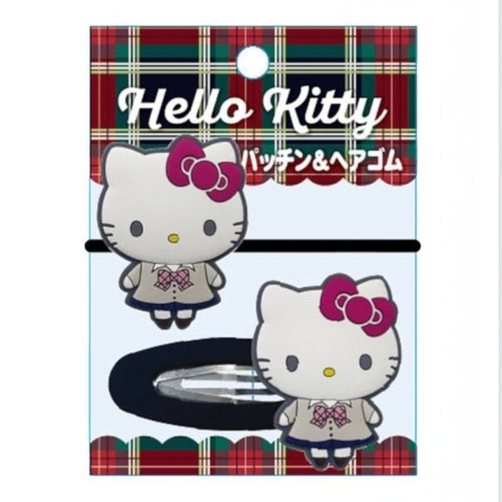 Hello Kitty hair accessory set on retail packaging, featuring a black hair tie with a Hello Kitty clip and a matching Hello Kitty hairpin, displayed on a light blue card with red plaid trim and Hello Kitty branding.