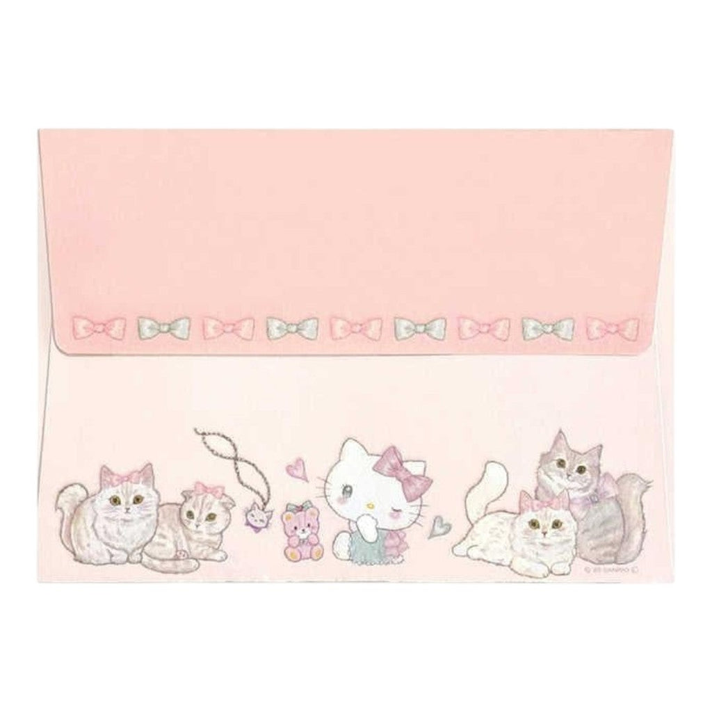 A pink Hello Kitty themed envelope or card with a decorated flap. The flap features a row of small bows and the bottom border is illustrated with various cute Hello Kitty cats, a teddy bear, and a heart.