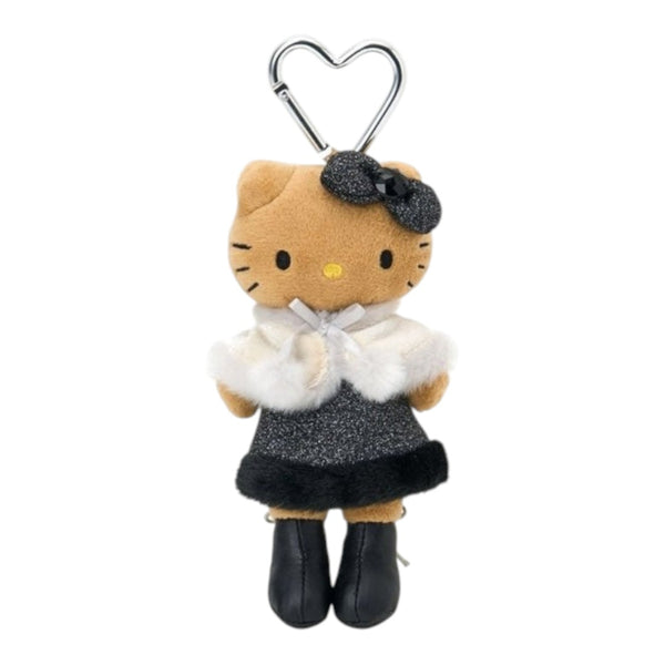 A Hello Kitty plush keychain accessory featuring the character in a tan outfit with a white faux-fur collar, a black glittery bow, a black glittery skirt, and black boots, attached to a silver metal carabiner on a plain white background.
