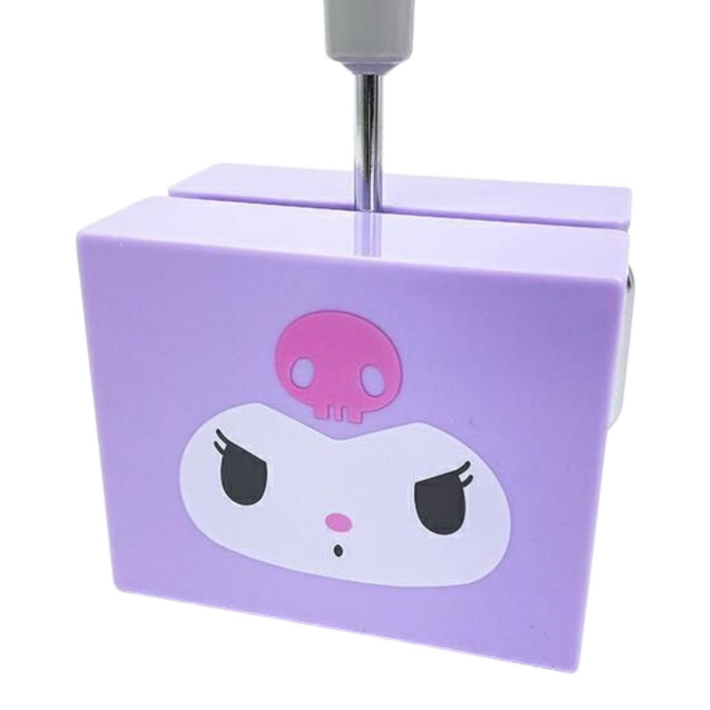 A purple plastic desk organizer featuring a cartoon face with a pink skull on the front, with a metal stand inserted at the top, shown against a plain white background.