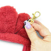 Red heart-shaped pouch with a gold clip and purple charm held by a hand on a white background