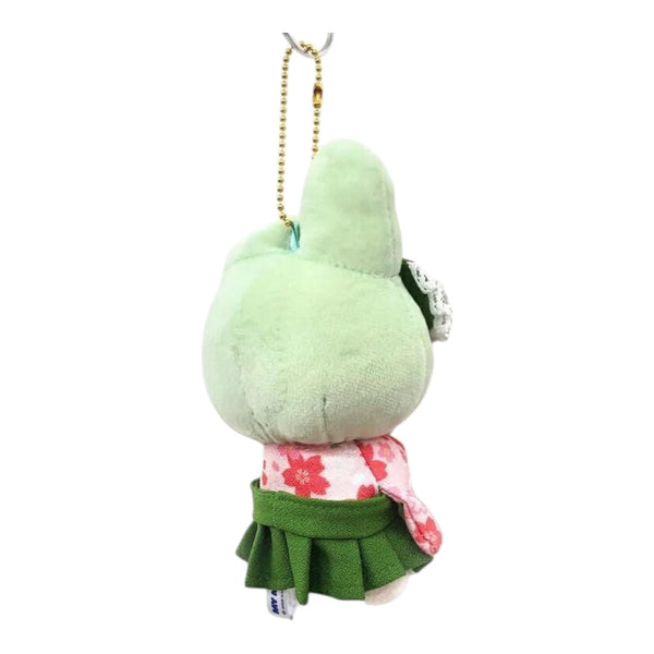 A small plush character keychain shown from the back, featuring a light green body, a green skirt, a pink floral top, and a gold metal chain.