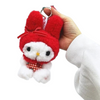 A hand holding a red and white plush character keychain with a metal key ring, against a plain light background.