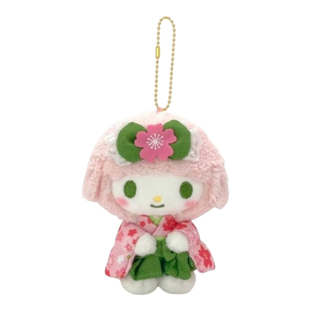 A small plush character keychain or bag charm with a gold ball chain. The character has a fluffy light pink head, green eyes, a pink flower headband, and a pink-and-green floral outfit, shown on a plain white background.