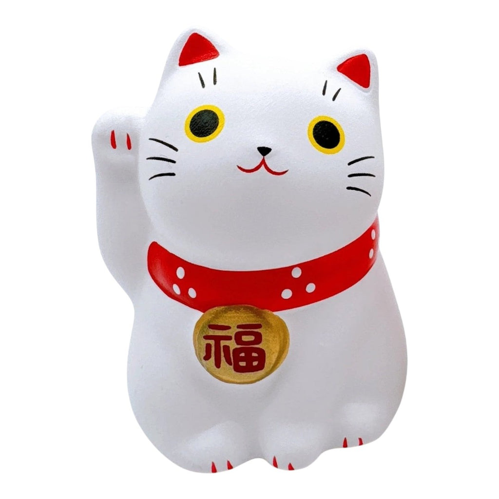 A white maneki-neko lucky cat figurine with a raised paw, featuring red accents on its collar and ears, yellow eyes, and a gold bell with a red Japanese character on its chest, set against a plain white background.