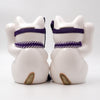 Back view of two Twinkle Glory Goenneko ceramic lucky cats with purple headbands and gold tails on a white background