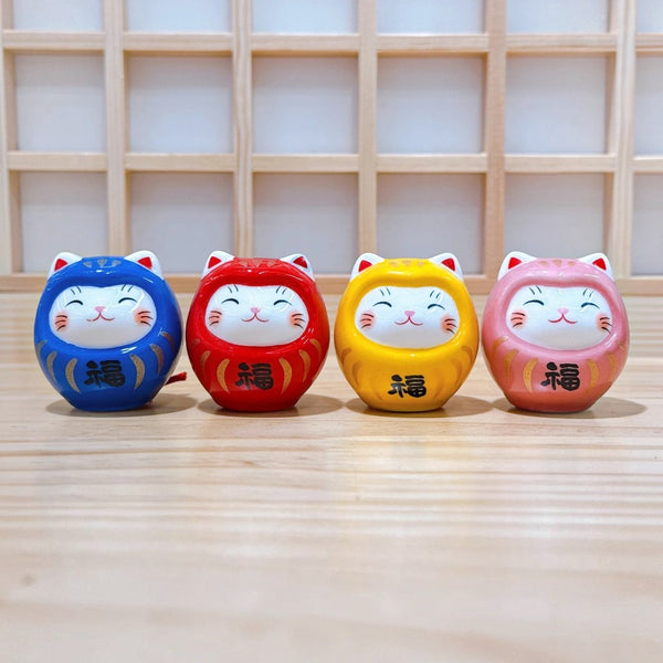Twinkle Glory set of four colorful hand-painted porcelain Daruma lucky cat mascots on a wooden surface