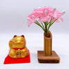 Twinkle Glory gold Yakushigama mini lucky cat figurine on a red mat next to a small bamboo vase with pink flowers