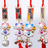 Twinkle Glory Japanese lucky cat charms in purple, blue, pink, and yellow resin with hanging bells and red cords.