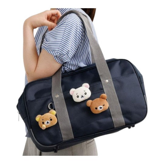 Twinkle Glory San-X Korilakkuma and Rilakkuma plush badges attached to a navy blue school bag