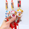 Twinkle Glory lucky cat charms in blue, pink, and yellow resin with hanging bells and red tassels for good fortune