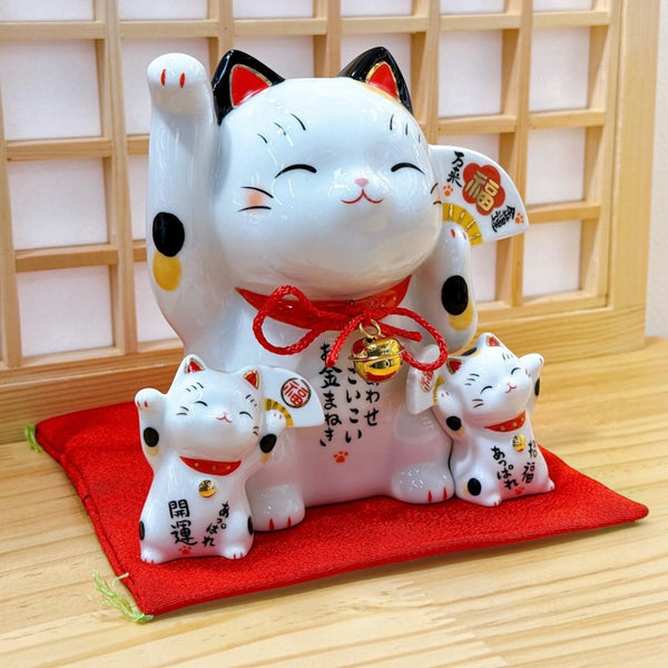 Twinkle Glory white ceramic Maneki Neko lucky cat piggy bank with two smaller cats on a red cushion