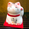 Twinkle Glory Japanese Maneki Neko lucky cat figurine with pink ears and red collar on a red felt base