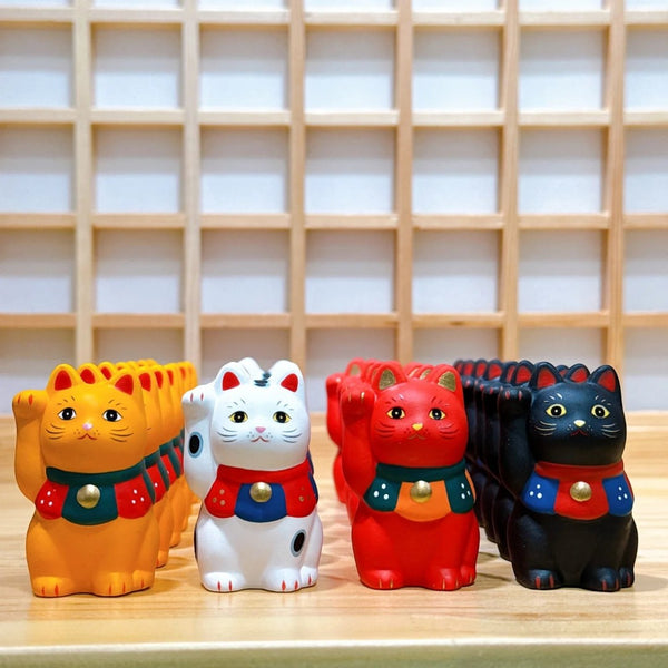 Twinkle Glory Yakushigama Maneki-Neko porcelain lucky cat figurines in orange, white, red, and black on a wooden shelf