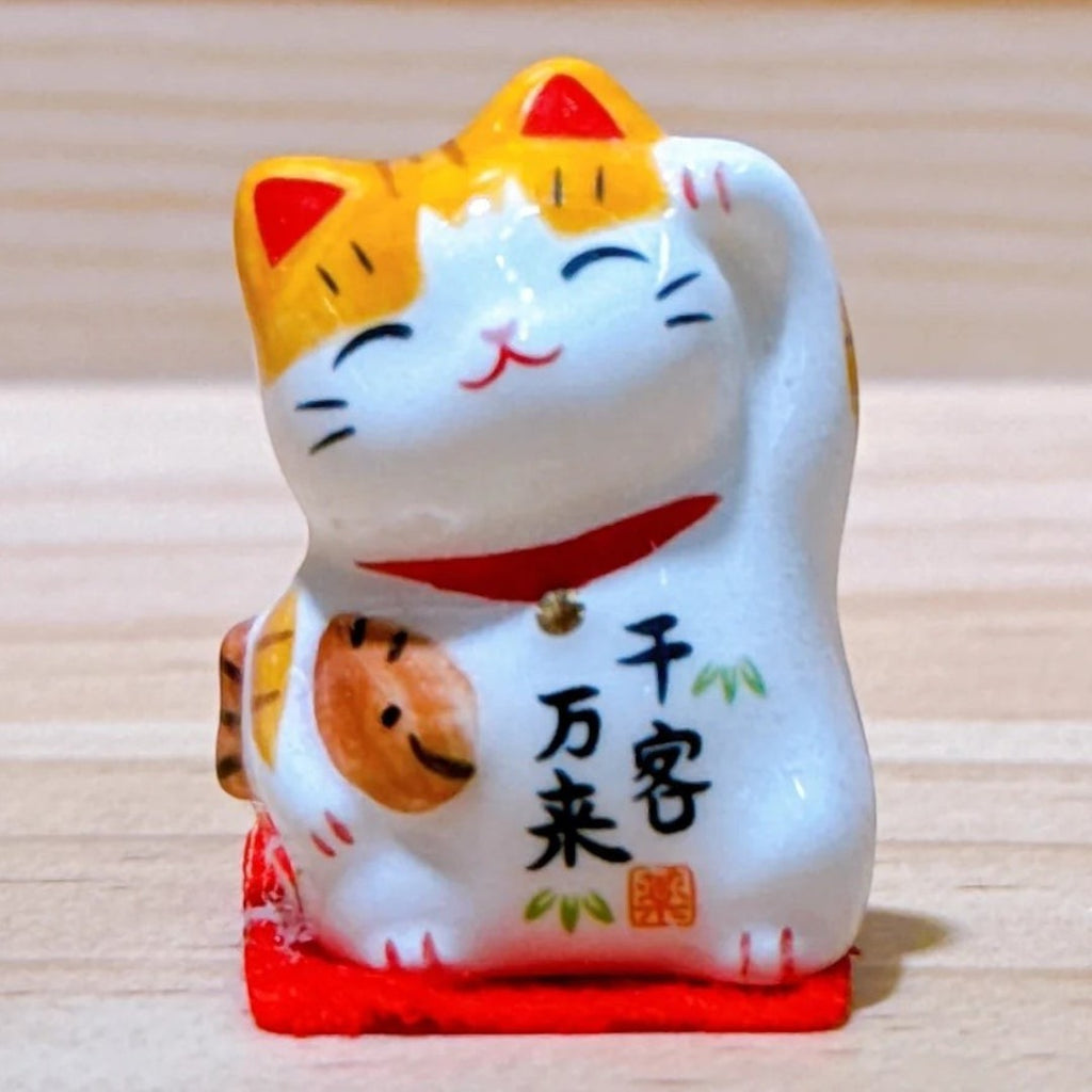 Twinkle Glory Yakushigama mini ceramic lucky cat figurine with orange and white markings and a raised paw