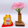 Twinkle Glory Yakushigama mini yellow lucky cat figurine on a red mat next to a small bamboo vase with pink flowers