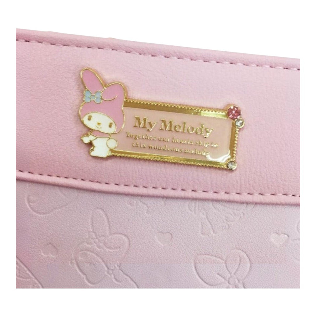 Twinkle Glory Sanrio My Melody bifold wallet in pastel pink with a decorative gold metal plaque and character detail.