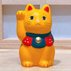 Twinkle Glory orange Yakushigama Maneki-Neko porcelain lucky cat figurine with a raised paw and red bib