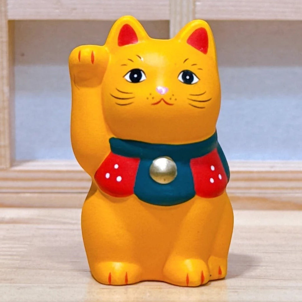 Twinkle Glory orange Yakushigama Maneki-Neko porcelain lucky cat figurine with a raised paw and red bib