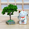 Twinkle Glory Yakushigama porcelain lucky cat figurine holding a crystal ball next to a miniature green tree