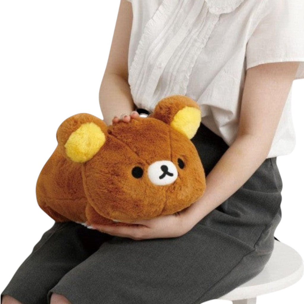 Twinkle Glory brown Rilakkuma laying down plush toy held by a person, featuring soft polyester and yellow ears