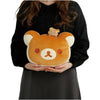 Twinkle Glory San-X Rilakkuma super mochi mochi plush pillow held by a person, featuring a soft tan bear face design.