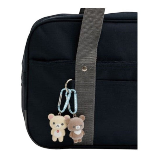 Twinkle Glory San-X Rilakkuma and Chairoikoguma plush carabiner keychains attached to a dark navy bag
