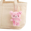 Twinkle Glory San-X Rilakkuma cherry blossom plush keychain in soft pink polyester hanging on a beige canvas tote bag