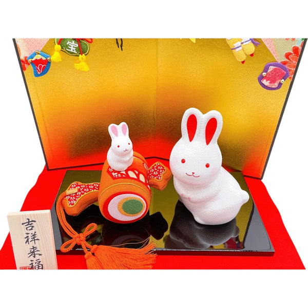 Twinkle Glory Ryukodo ceramic zodiac rabbit figurines with a lucky gavel on a black display stand and gold backdrop.