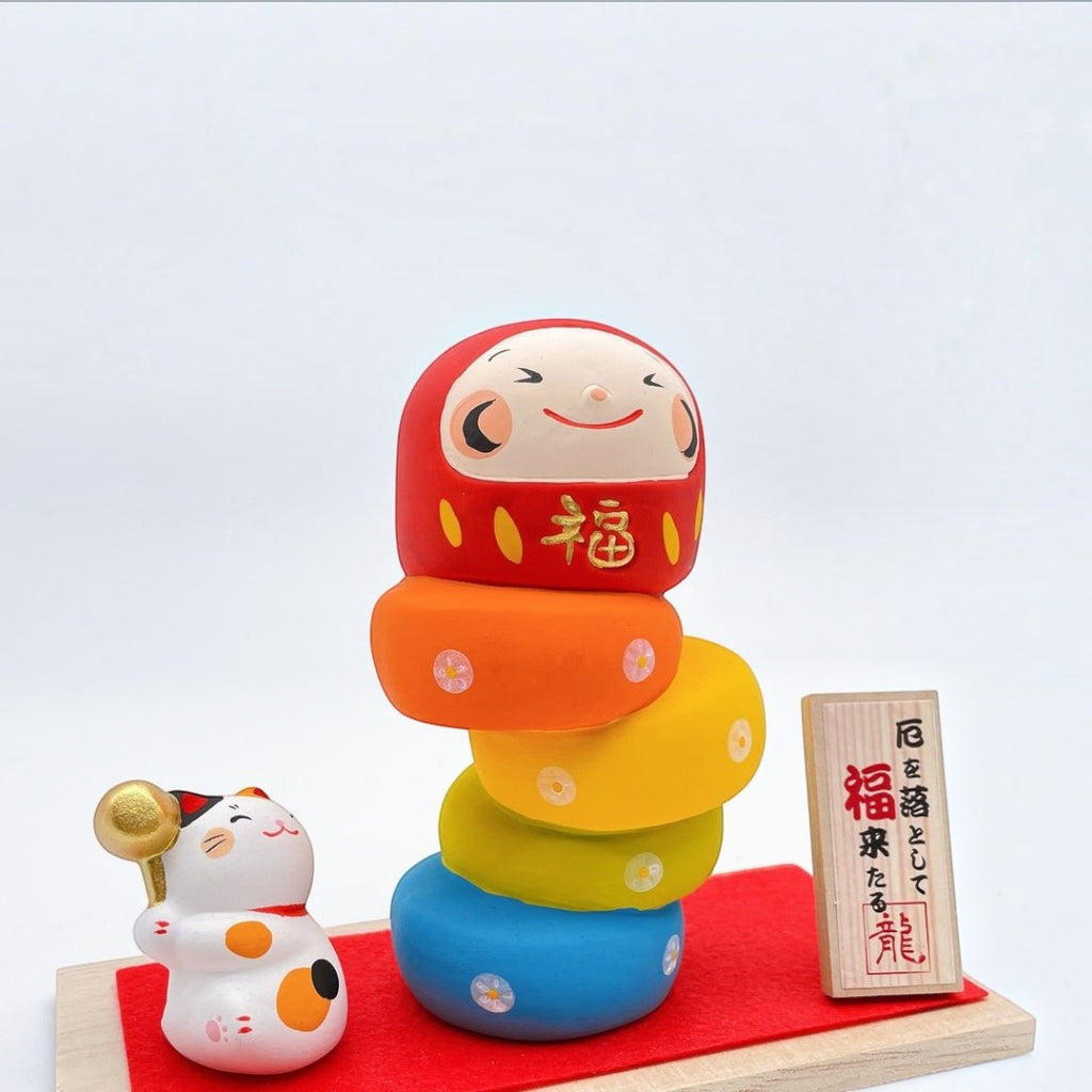 Twinkle Glory Ryukodo porcelain Daruma Otoshi stacking game with a hand-painted lucky cat on a red cloth and wood base