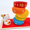 Twinkle Glory Ryukodo porcelain Maneki Neko lucky cat figurine with a colorful stacked Daruma Otoshi game on red cloth