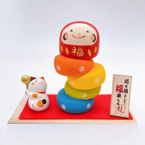 Twinkle Glory Ryukodo porcelain Maneki Neko lucky cat and colorful Daruma Otoshi stacking game set on a red cloth.