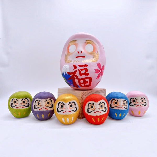 Twinkle Glory Japanese six-color paper Daruma dolls featuring a large pink centerpiece and smaller colorful figures.