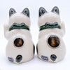 Back view of two Twinkle Glory Yakushigama ceramic lucky cats with green collars and black spots on a white background