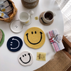 Cup of coffee on a brown Smiley Face coaster next to blue, yellow and white Smiley Face mat coasters 