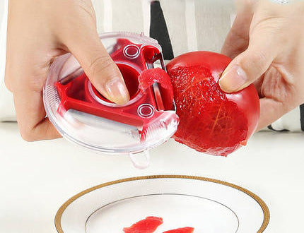 Red 3 in 1 kitchen peeler peeling a tomato